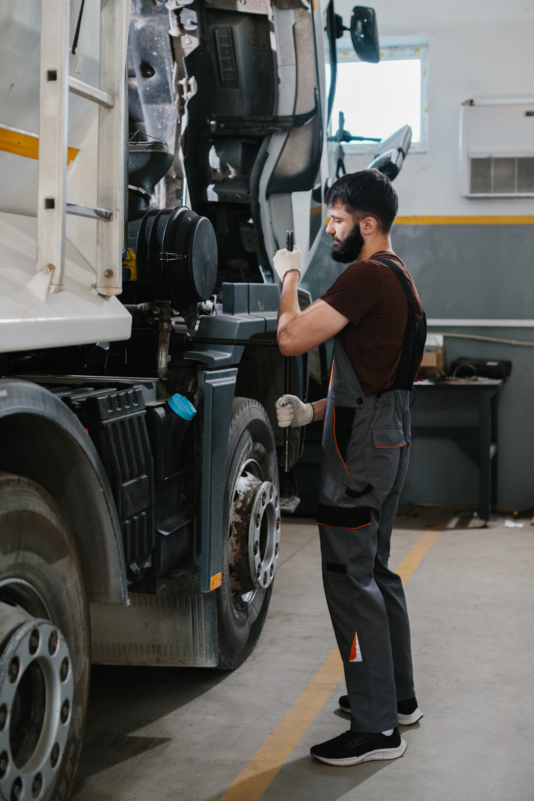 Mechanic repairing truck engine in garage workshop